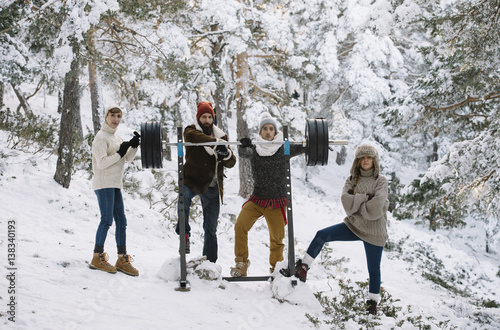 People with barbell in winter forest