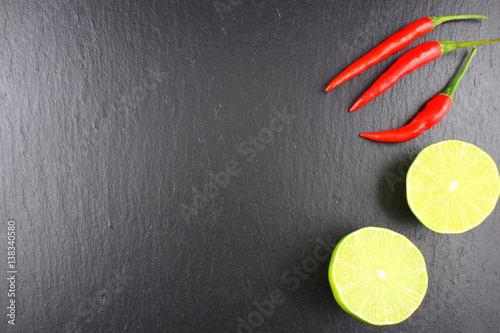 fresh thai chili peppers and lime on a slate plate food background texture
