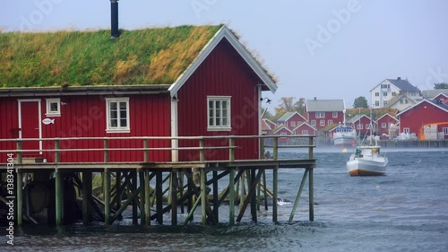 Rorbuer with grass-covered roof at Gulf of Reine in Lofoten. Strong wind lifts the water drop above the surface. photo