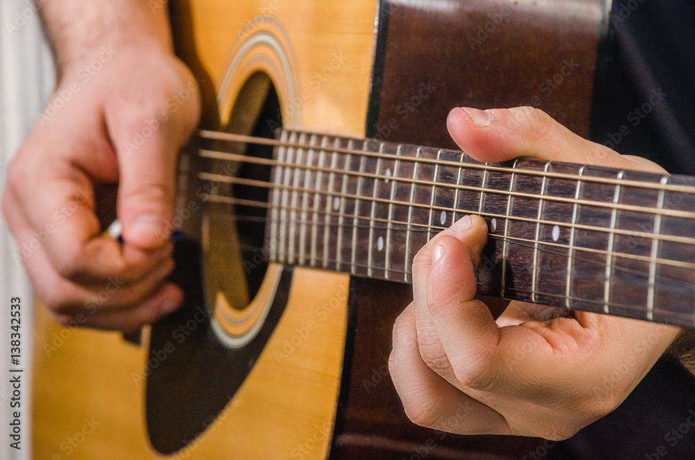 Fototapeta premium Skilled hands play yellow acoustic guitar