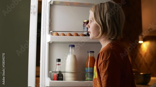 Two young blonde brothers opening fridge looking for food in slowmotion