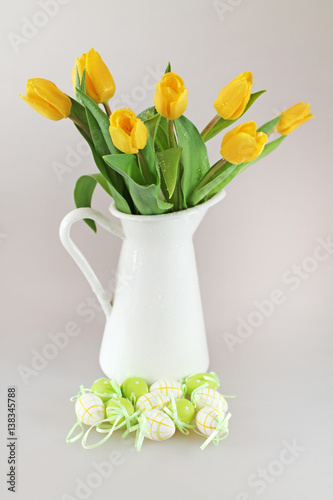 Yellow garden tulips in jug with easter eggs