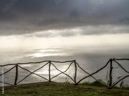 Grey cloudy mood above the ocean, wooden fence, Portugal, Madeir