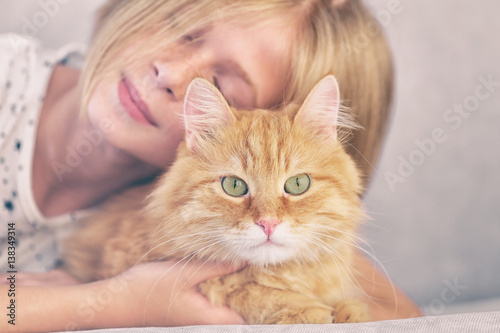 Fototapeta Naklejka Na Ścianę i Meble -  Attractive little girl with red fluffy cat on sofa in room