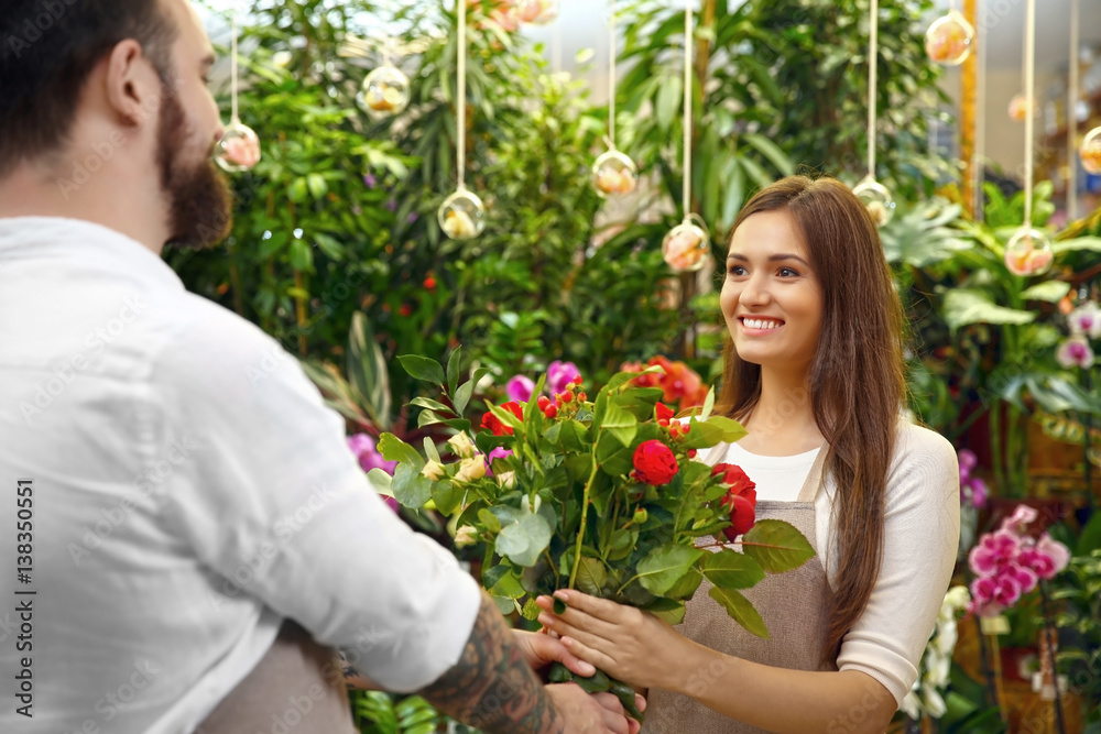 Male and female florists with beautiful bouquet in greenhouse