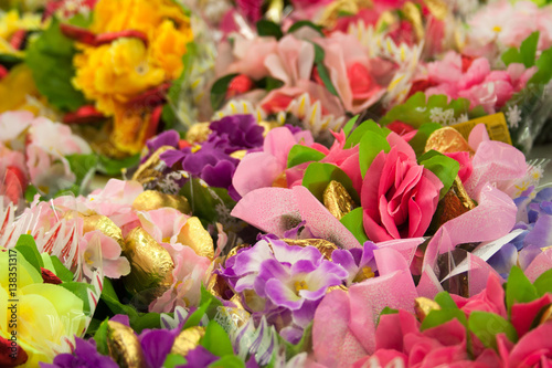 festive bouquet of artificial flowers and chocolates close-up on the market