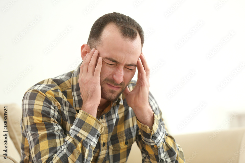 Handsome man suffering from headache at home Handsome man suffering from headache at home