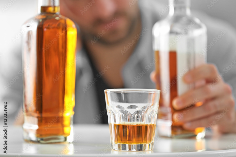 Bottle and glass of whisky with blurred man on background Bottle and glass of whisky with blurred man on background