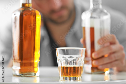 Bottle and glass of whisky with blurred man on background