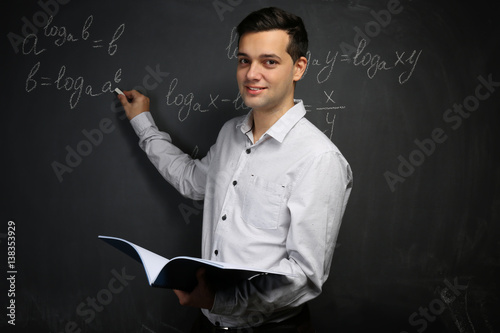Handsome young teacher writ...