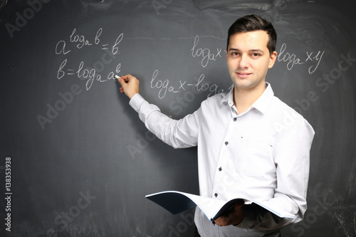 Handsome young teacher writ...