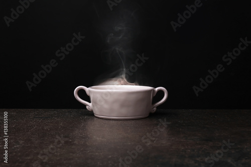 Bowl with hot water on dark background