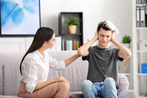 Young female psychologist working with teenager boy in office