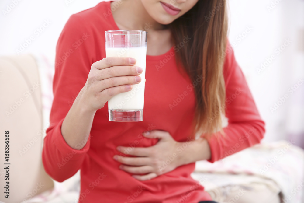 Woman with stomach pain holding a glass of milk Woman with stomach pain holding a glass of milk