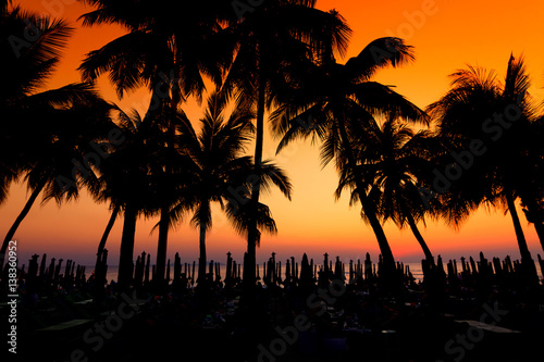 Dark silhouettes of palm trees and beach umbrella with amazing cloudy sky sunset at tropical beach in Pattaya Thailand. Coconut Tree with Beautiful and romantic sunset in Maldives island. color filter