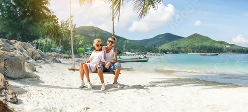 mature couple rest on a swing at tropical beach