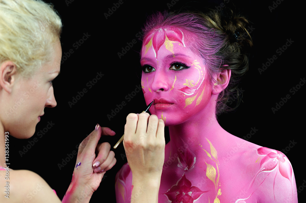 Bodypaint master in work, paints a model for a photo shoot