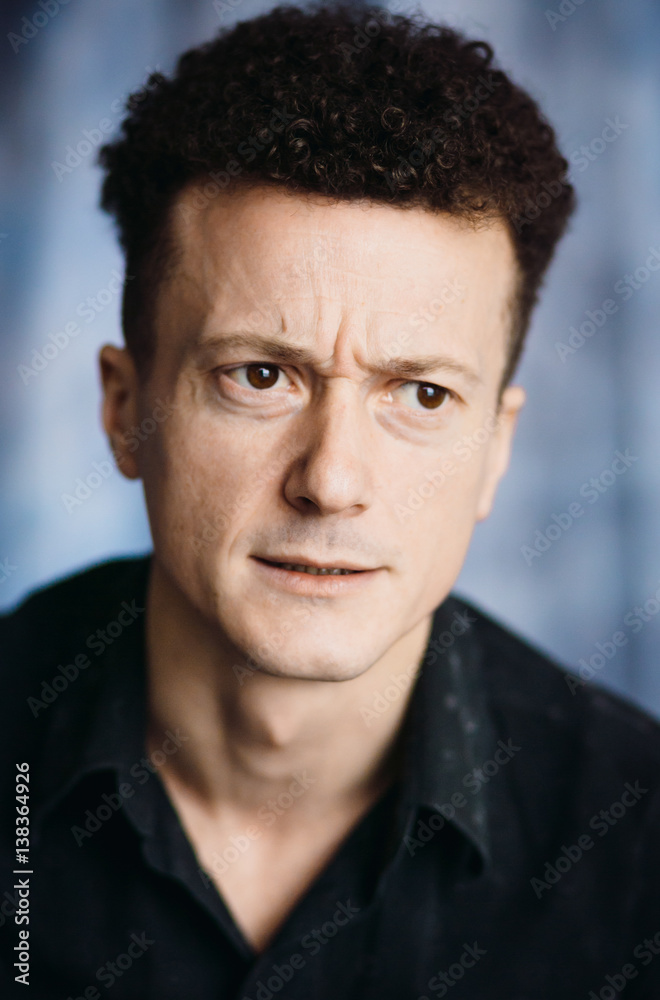 Obraz premium Thoughtful man looks funny posing in black shirt