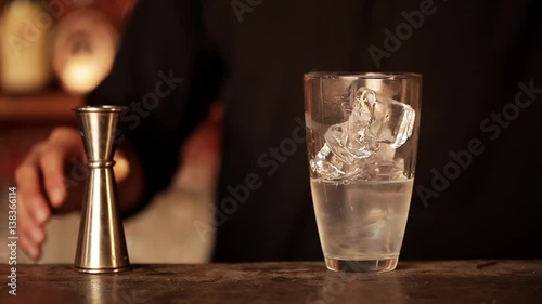 Bartender adding shot of cranberry juice to cocktail mixture in shaker