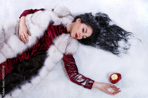 Woman laying on a snow near the bitten apple photo