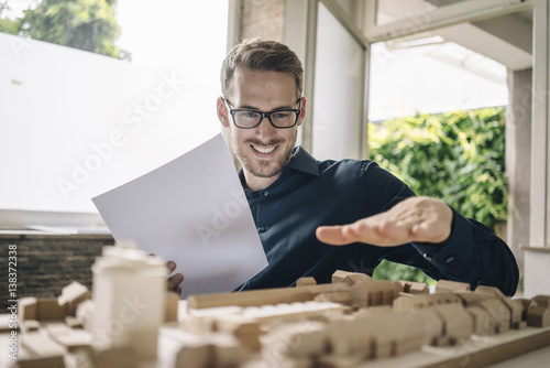 Smiling architect looking at urban development model