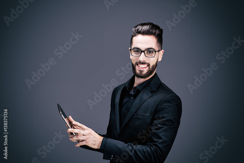 Portrait d'un jeune homme d'affaires souriant, tenant une tablette tactile dans ses mains
