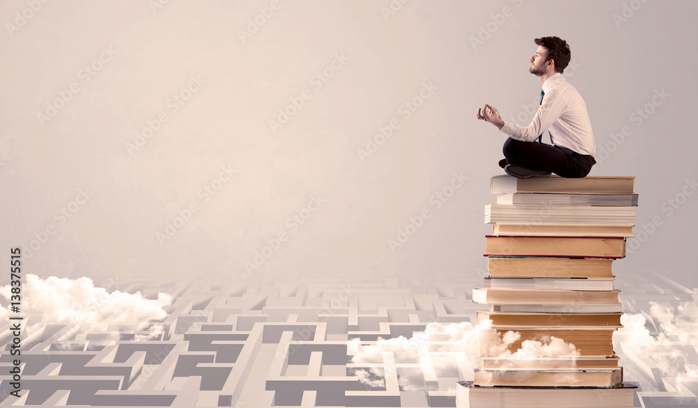 Businessman sitting on books in labirynth Businessman sitting on books in labirynth