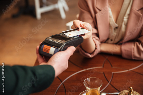 Attractive young pretty woman sitting in cafe pays the order © Drobot Dean