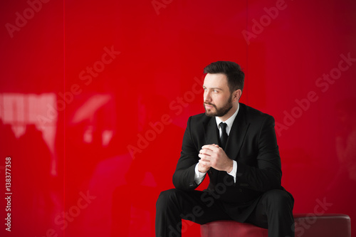 man in black suit on red background