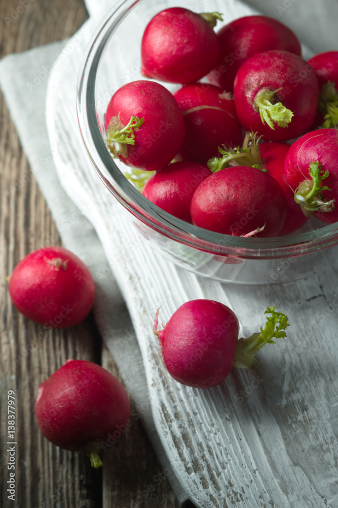 Red radish in a glass bowl on a wooden stand Red radish in a glass bowl on a wooden stand