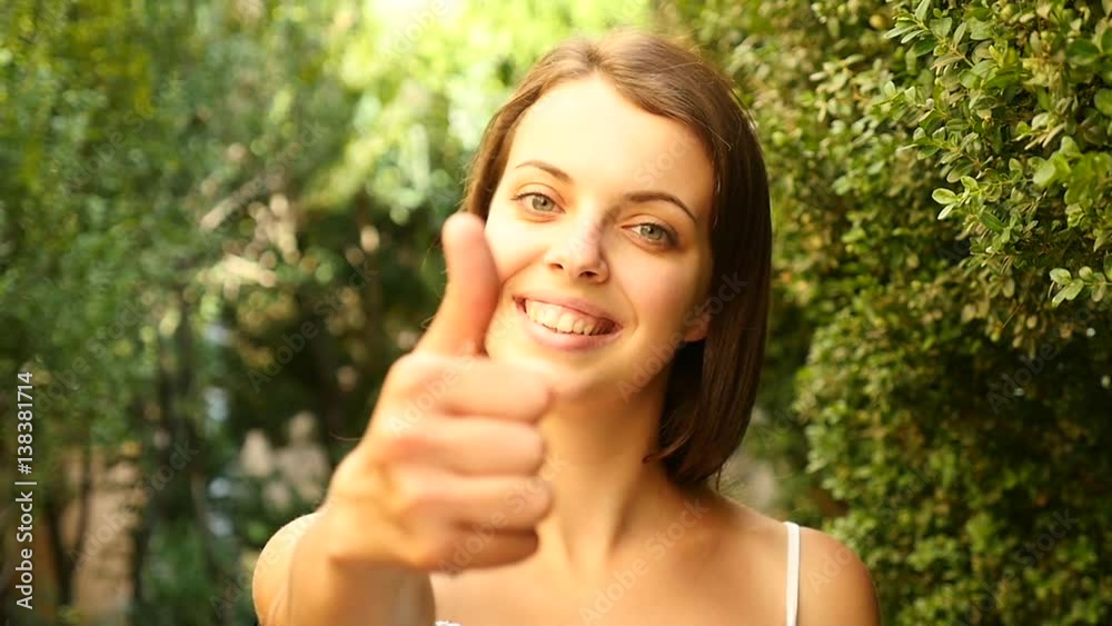 Girl laughing and show big finger up. The Action in Real Time. Beautiful cheerful girl smiling and showing a thumbs up. Pretty young girl with brown hear show like symbol. Girl laughing and show big finger up. The Action in Real Time. Beautiful cheerful girl smiling and showing a thumbs up. Pretty young girl with brown hear show like symbol.