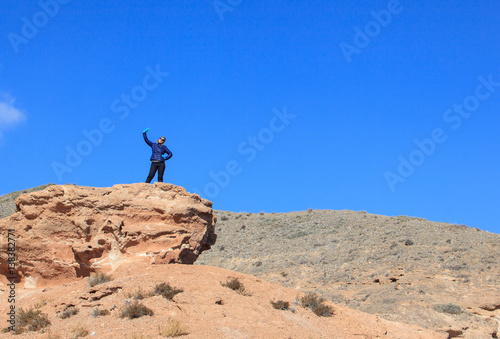 Happy woman standing on the top of the hill with raised hands  and enjoy the view     