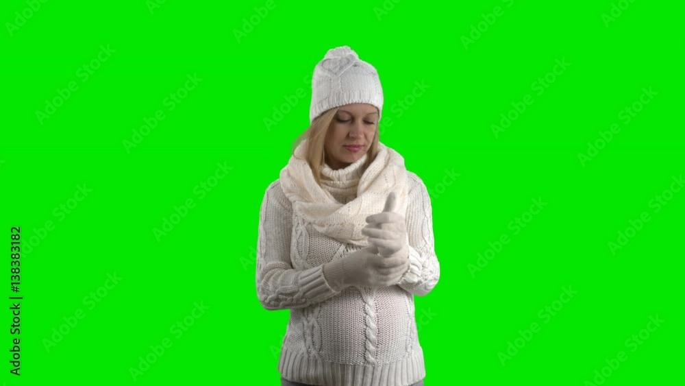 Pregnant woman wearing a white woolen sweater scarf knitted cap and gloves posing against green screen Pregnant woman wearing a white woolen sweater scarf knitted cap and gloves posing against green screen