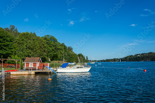 En brygga ute i Stockholms skärgård med en vit båt förtöjd photo
