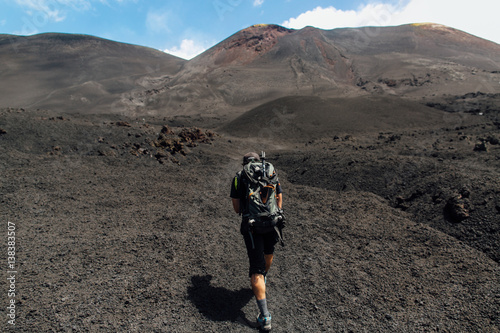 Hiker with rucksak climbing at crater volcano Etna in Sicily photo