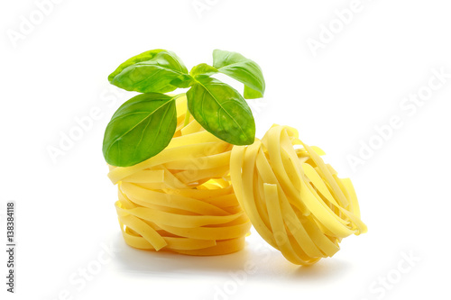 Raw fettuccine pasta with basil isolated on white background