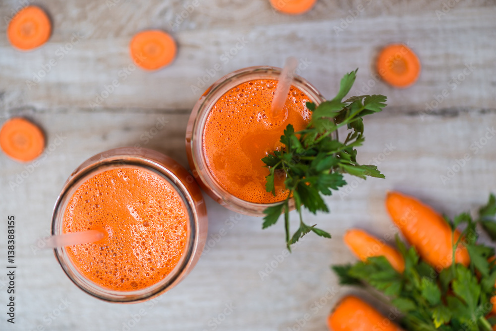 Fresh carrot juice in bottles on a grey wooden table Fresh carrot juice in bottles on a grey wooden table