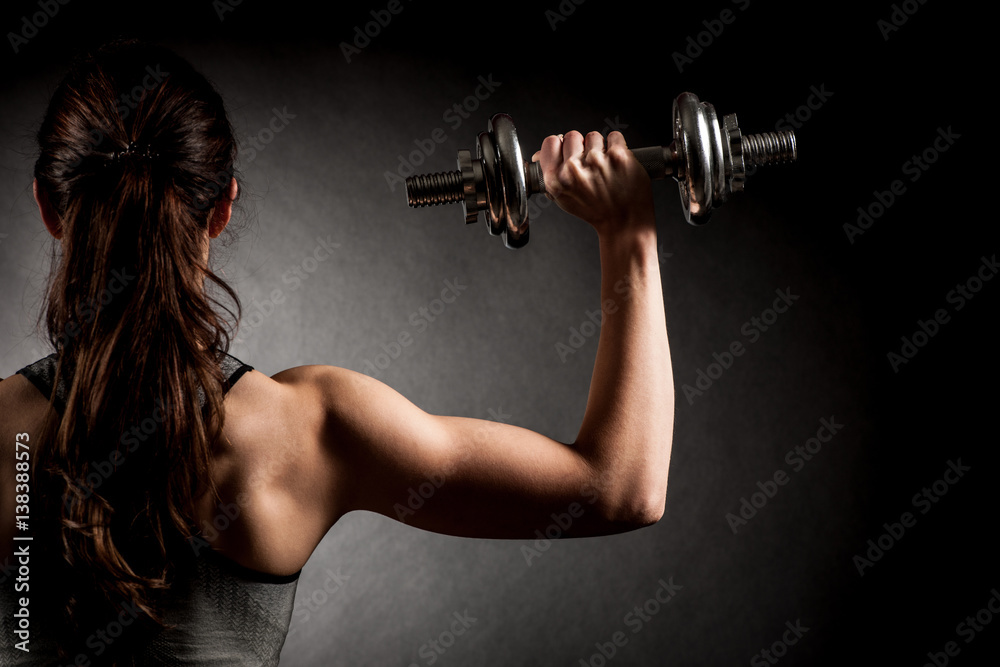 Φωτογραφία Atractive fit woman works out with dumbbells as a fitness conceptual over dark b