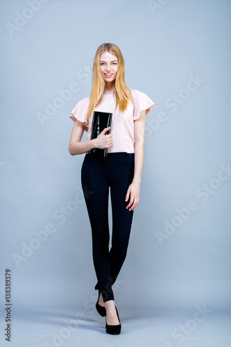 Jeune femme souriante,en pied, un sac à la main, le regard vers l'objectif © Warpedgalerie