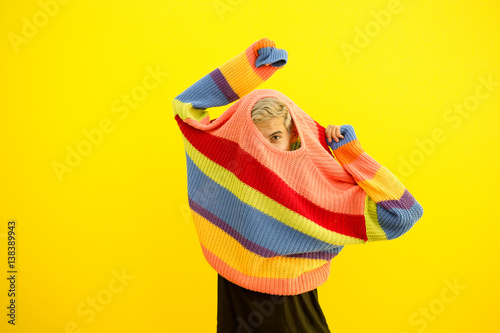 Man peeking out of sweater on yellow background photo