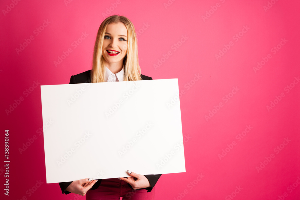 Young business woman holds blank banner isolated over pink background Young business woman holds blank banner isolated over pink background