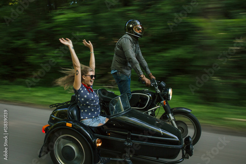 Blurred motion image of couple riding motorbike with sidecare photo