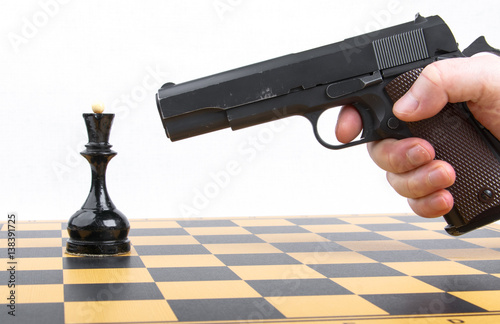 hand with gun took aim at chess piece