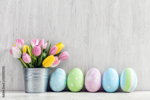 Easter eggs and a spring bouquet of tulips on a wooden table.