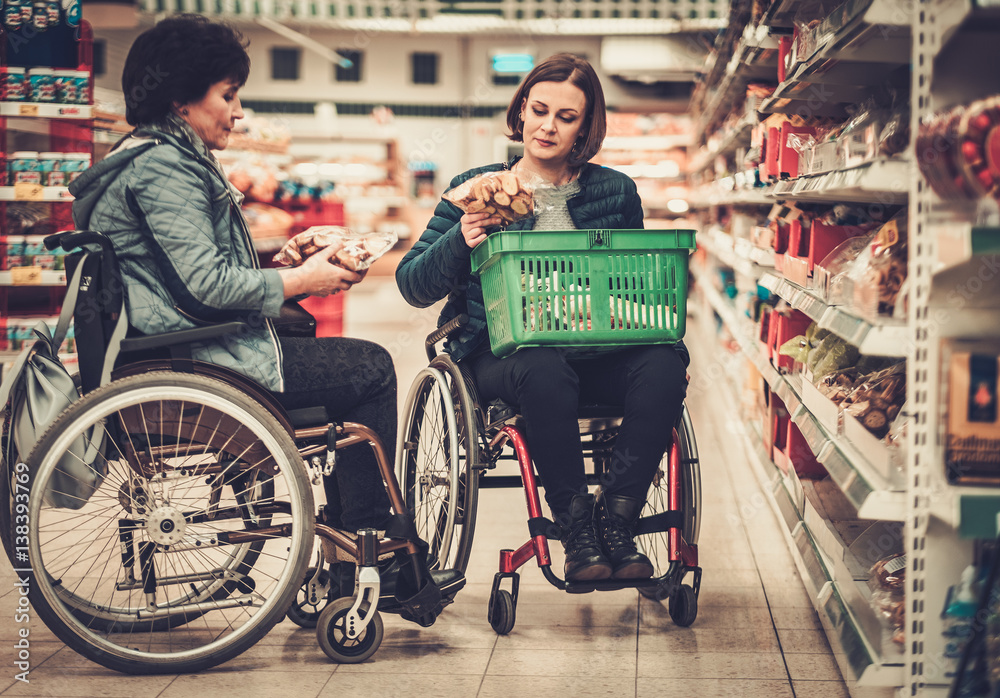 Two disabled woman in a wheelchairs in a grocery store Two disabled woman in a wheelchairs in a grocery store