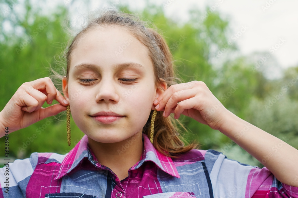 The girl child tries on earrings from the seeds of the birch. The girl child tries on earrings from the seeds of the birch.