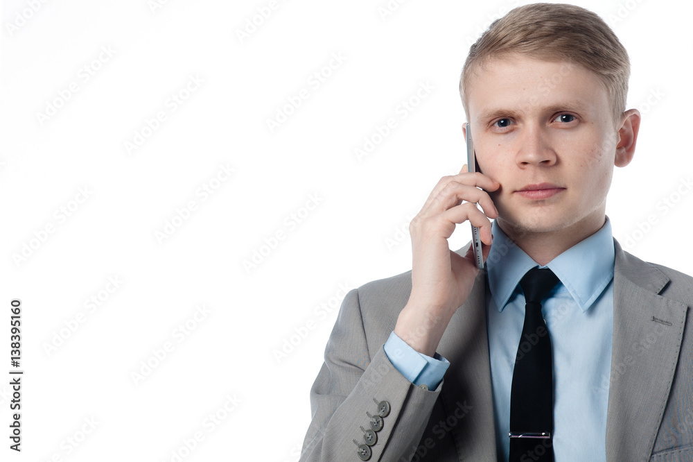young businessman talking on the phone and looks at you. in a business suit on a white background. young businessman talking on the phone and looks at you. in a business suit on a white background.