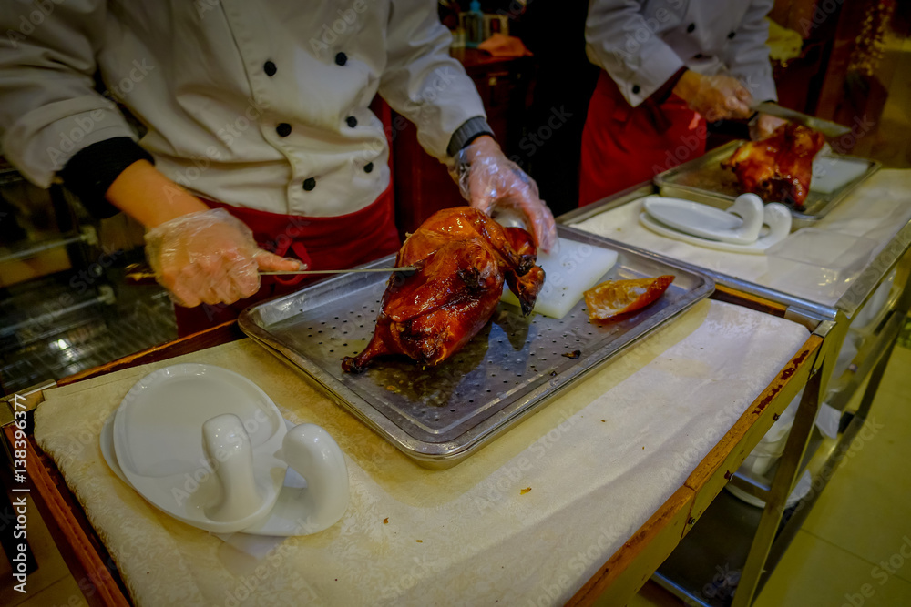 BEIJING, CHINA - 29 JANUARY, 2017: Professional chef cutting a famous traditional peking duck using knife, delicious looking meat