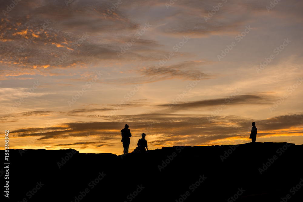 silhouette of three people over rocks