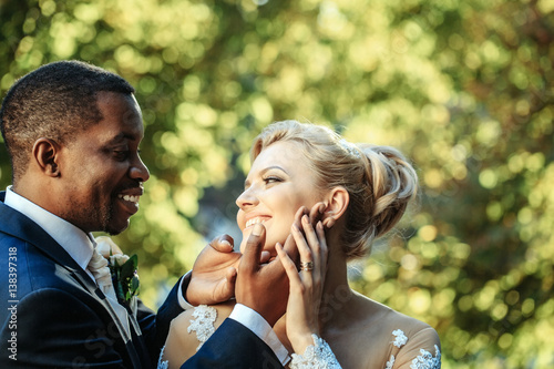 Loving groom touches face of adorable bride
